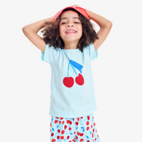 A kids wearing a cherry graphic t-shirt smiling with their hands on their head.