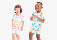 2 kids standing side by side clapping wearing our new organic PJs in beach ball and starfish.