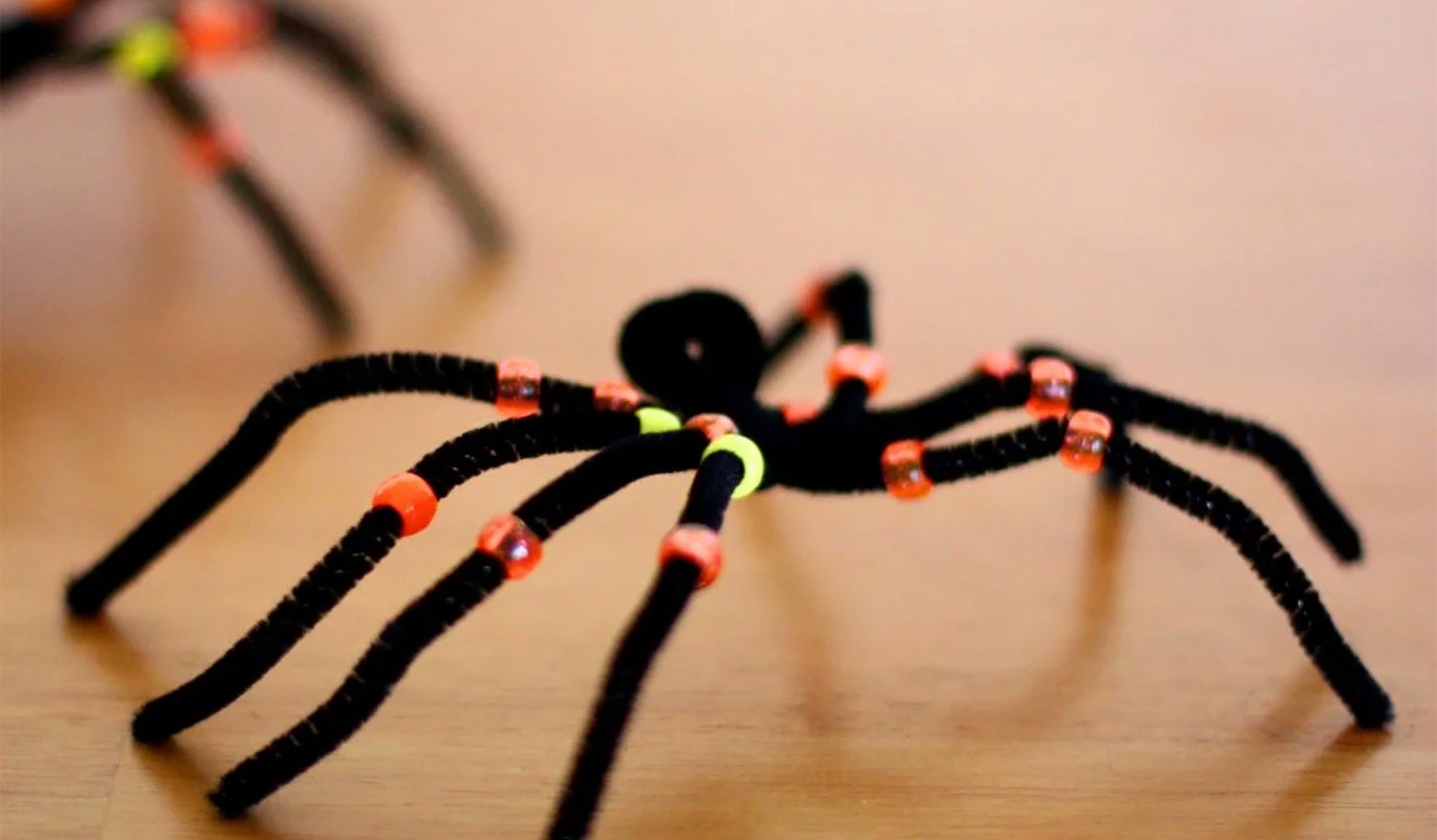Photo of spider made with black pipe cleaners and yellow and orange beads.
