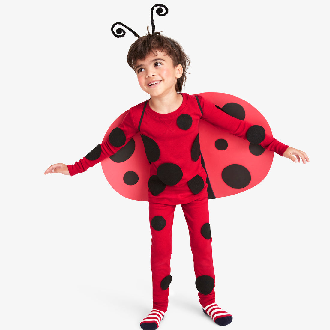 Child wearing a red ladybug outfit with curled black antennae