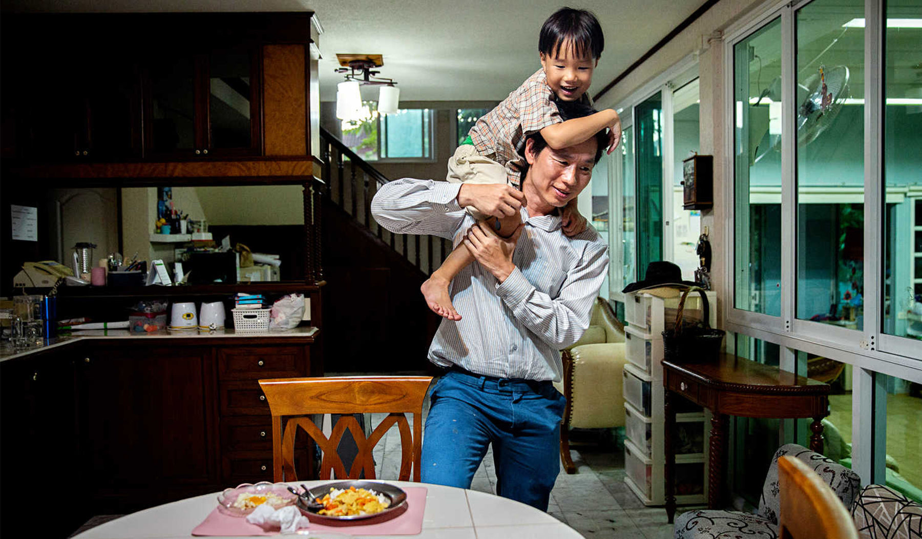 father holding his son on his shoulder in their kitchen