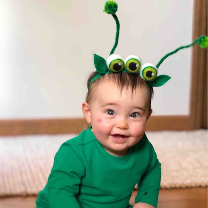 Alien: A baby wearing a green outfit with an alien inspired headband.