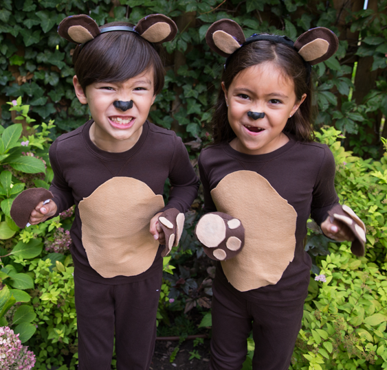 Bears: Two kids wearing brown outfits with tan patches on the stomach and bear inspired ear headbands and paws