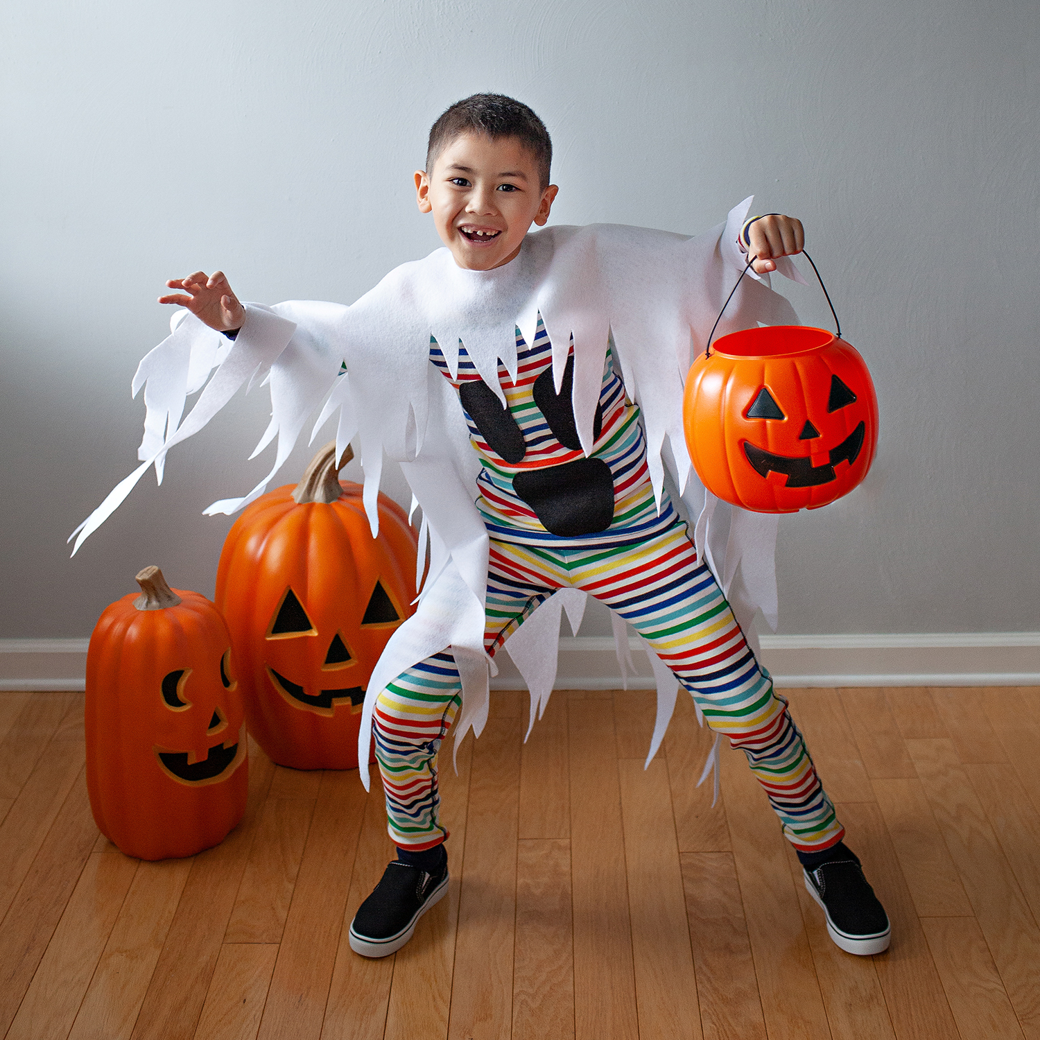 Ghost: One child wearing a rainbow striped outfit with a white piece of fabric with a shredded bottom overtop.