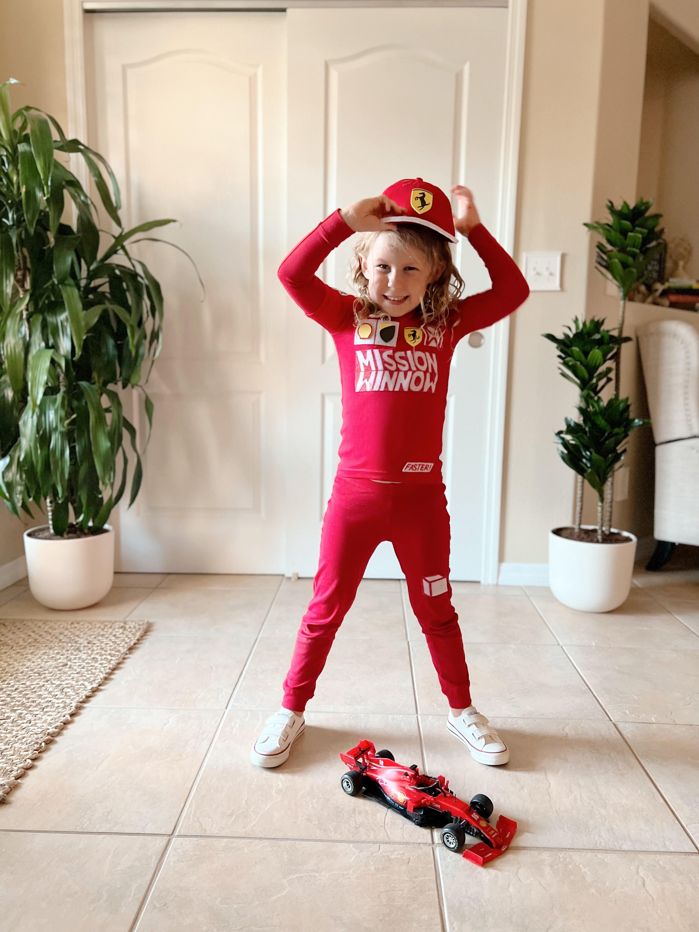Race Car Driver: A child wearing a red outfit to resemble a race car driver.