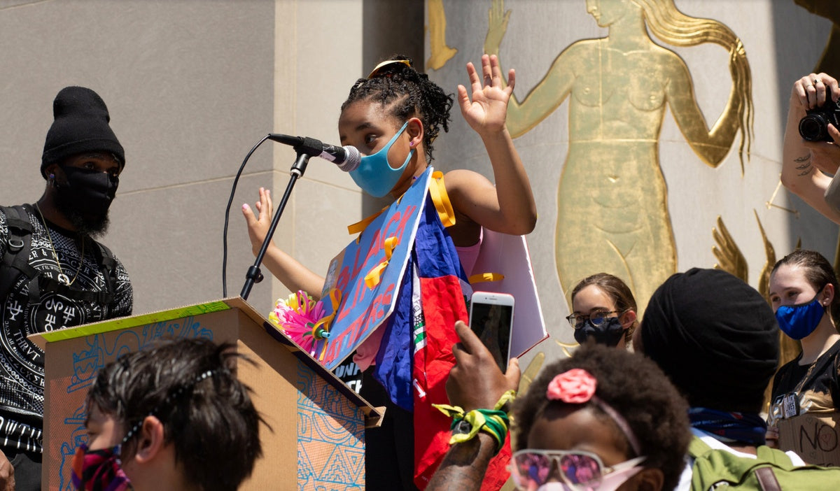 young girl wearing mask speaking at the podium of a Black Lives Matter protest in Brooklyn