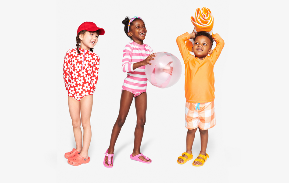 3 children in mix-and-match swim styles in shades of red, orange, and pink