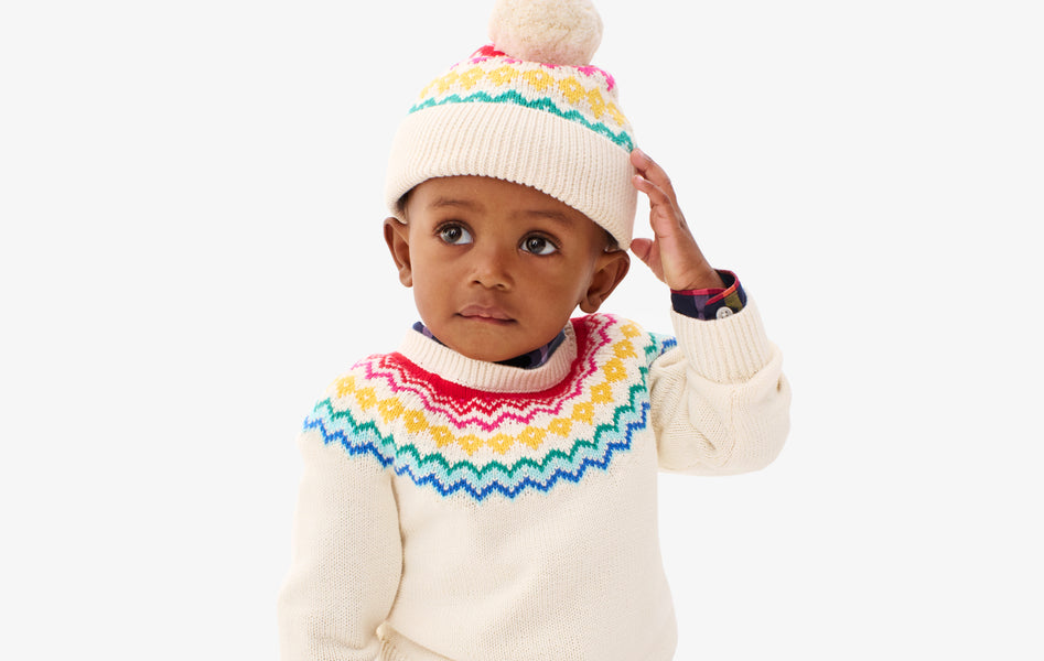 A baby wearing our new fair isle sweater with matching fair isle beanie.
