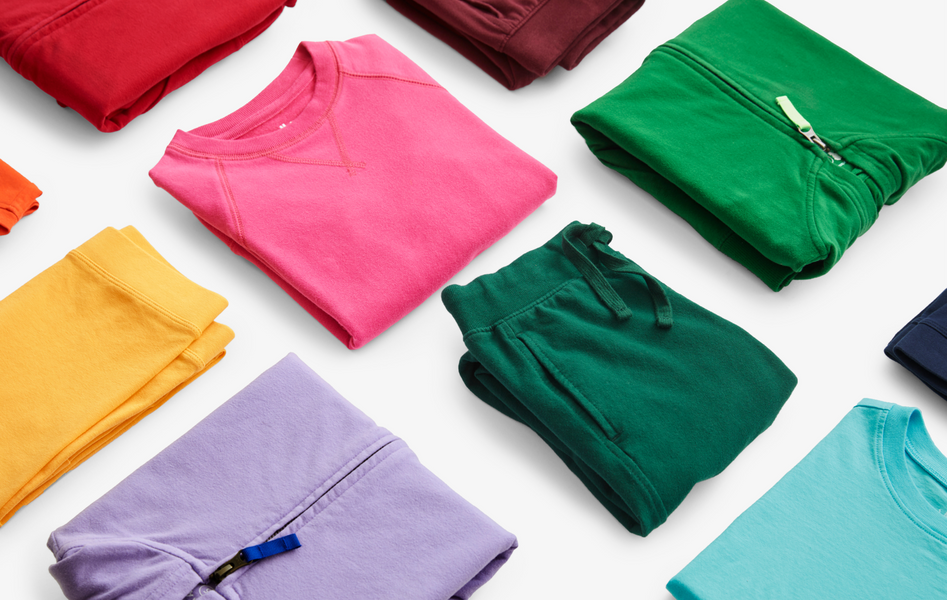 Our solid and basic tees, joggers, and sweatshirts neatly folded in a rainbow order. 