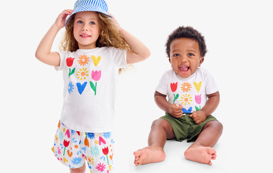 Two young children standing side by side, wearing matching white t-shirts with a rainbow star pattern and colorful shorts.