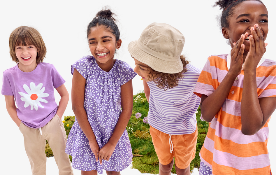 A group of kids wearing differeing tees, dresses, and shorts in our lavender and cantaloupe colors 