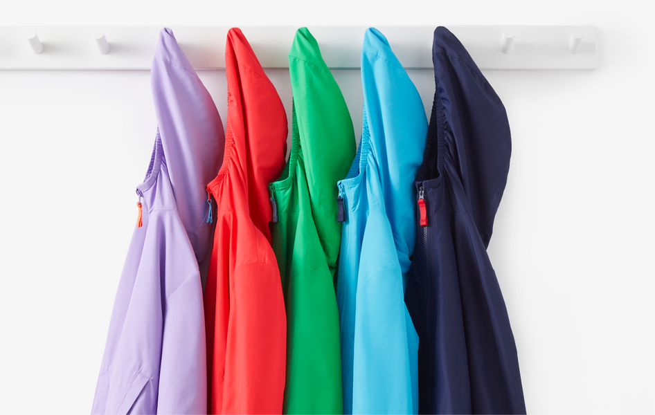 An image of 5 windbreakers hanging on a hook in rainbow order