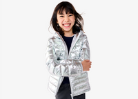 A child smiling wearing our silver lightweight puffer jacket.