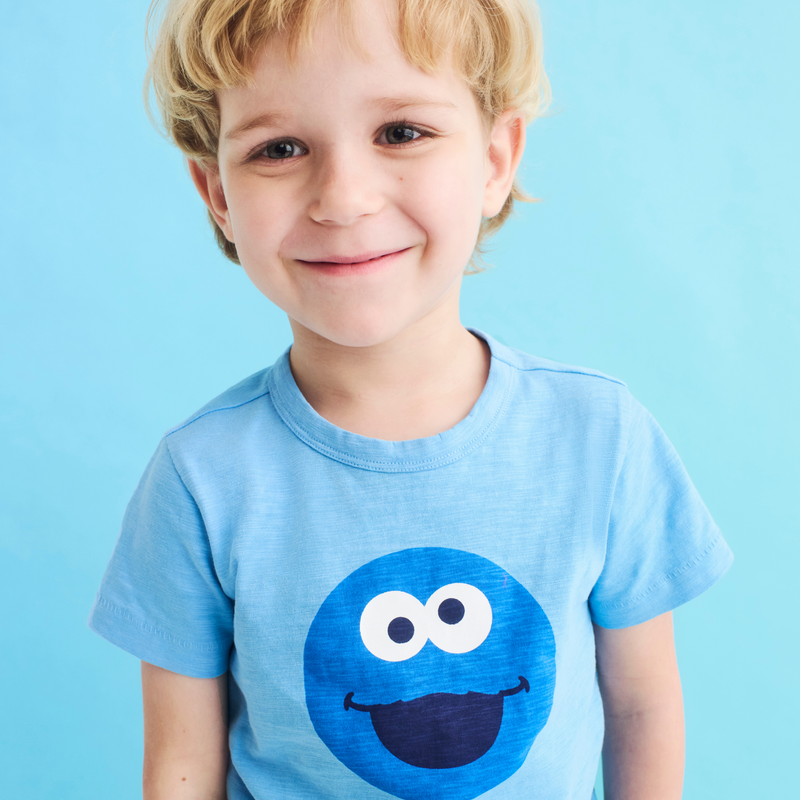 Child wearing a blue t-shirt with a cartoon character on a light blue background