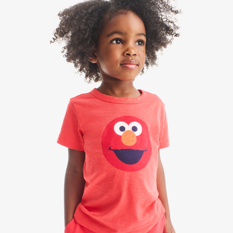 Child wearing a red t-shirt with a character face design on a white background