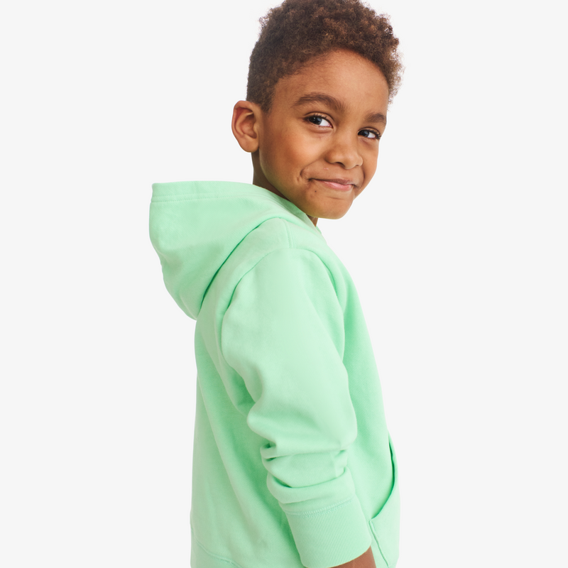 Child wearing a light green hoodie on a white background