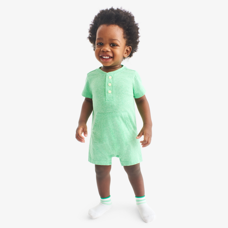 Child wearing a green romper on a white background