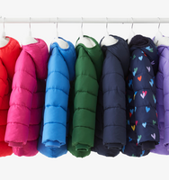 7 of our kids parka puffers hanging on a rack in rainbow order.