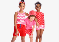 3 kids standing shoulder to shoulder laughing together. All wearing our new swim in poppy and gumball colors.