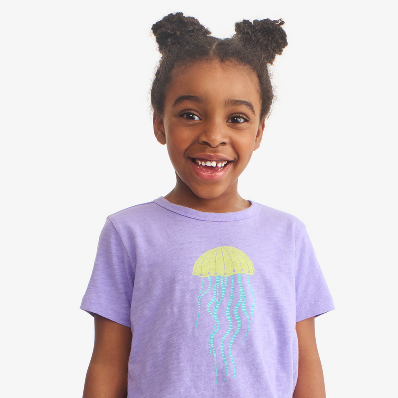 Child wearing a purple t-shirt with a jellyfish graphic on a white background
