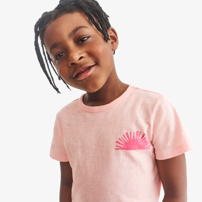 Child wearing a pink t-shirt with a sun design on a white background
