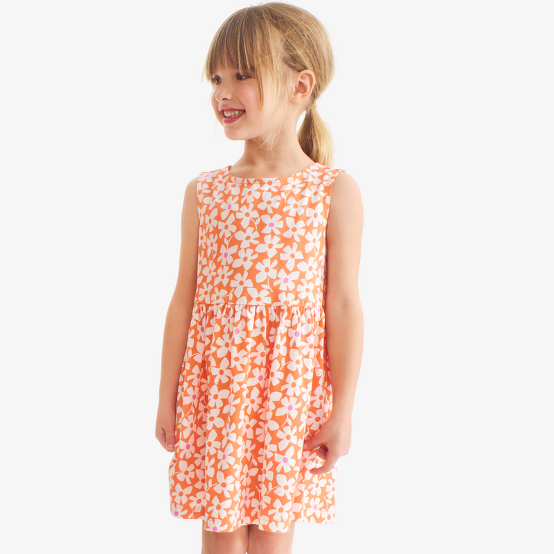 Young girl wearing an orange floral dress on a white background