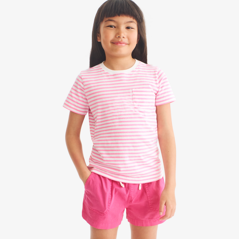 Young girl wearing a pink and white striped shirt and pink shorts on a white background