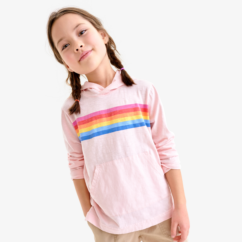 Young girl wearing a pink hoodie with rainbow stripes on a white background
